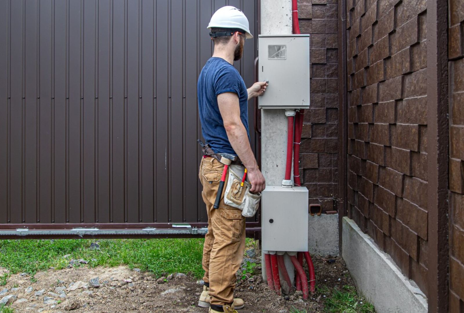 Electrician in a hard hat opening an outdoor meter cabinet