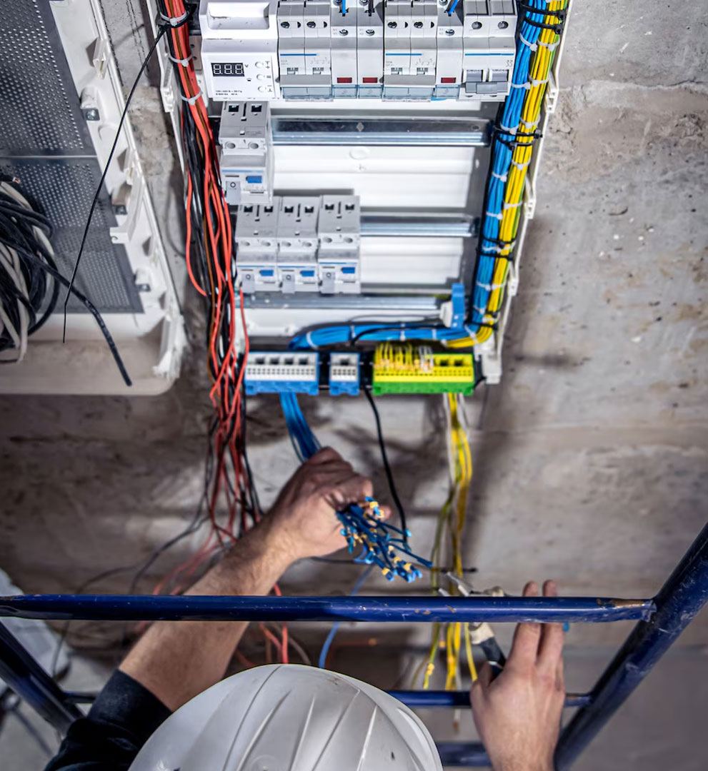 Overhead view of a worker on a tower wiring a distribution board