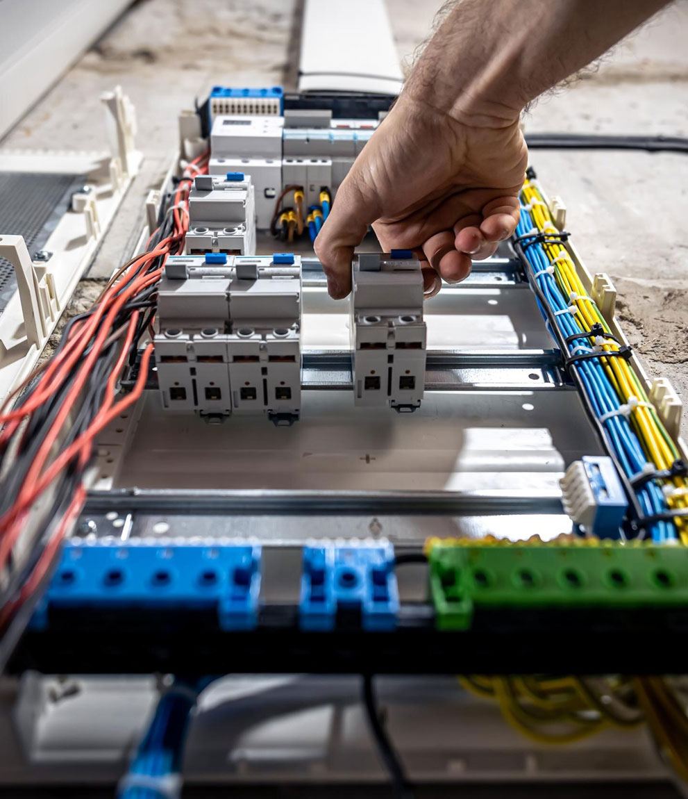 Hand clipping a circuit breaker onto the DIN rail of an open panel