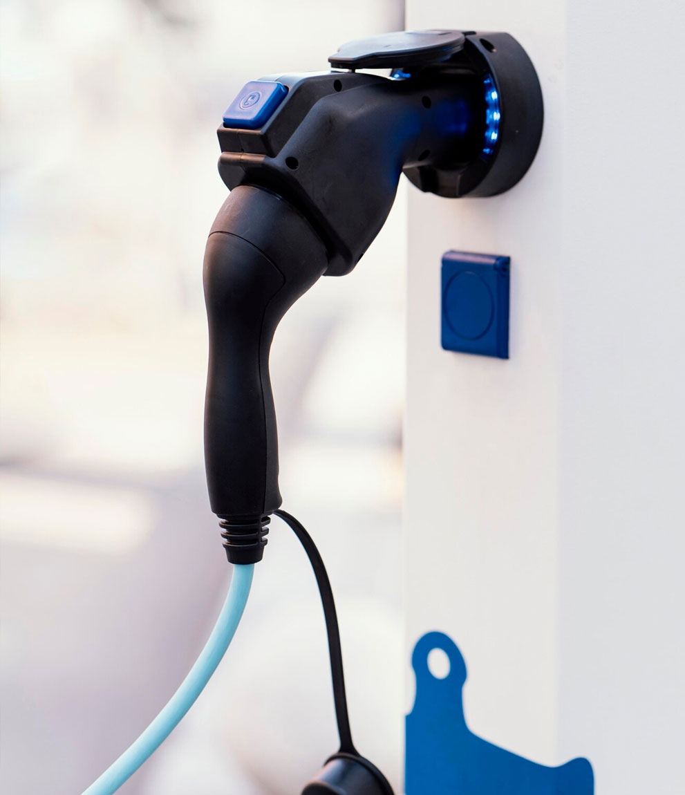 Black charging gun docked in a wall-mounted charge point with blue LED ring