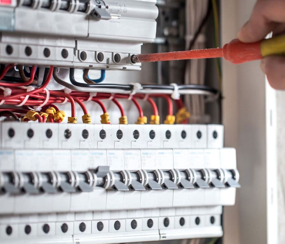Screwdriver tightening a terminal on a densely populated distribution board