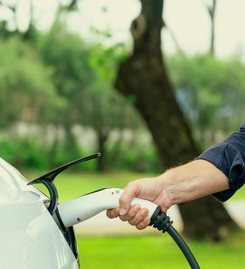Charging cable being plugged into the port of a white electric car