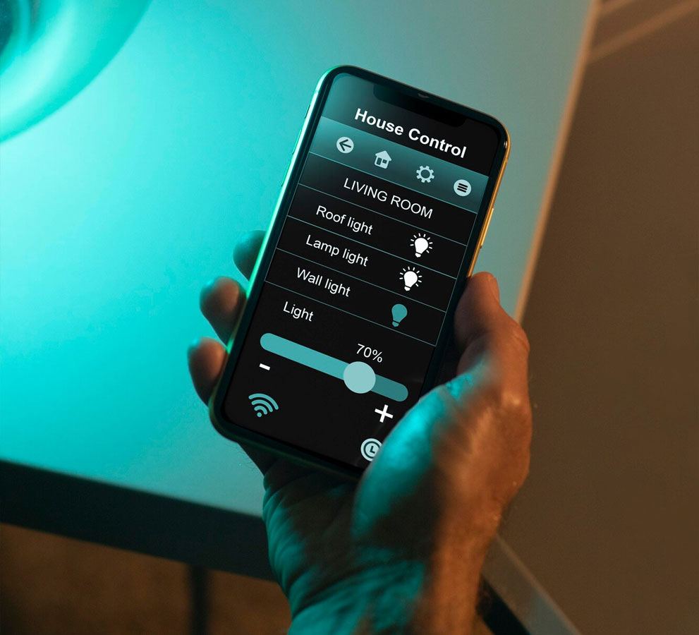 Hand holding a phone dimming living room lights to 70 per cent
