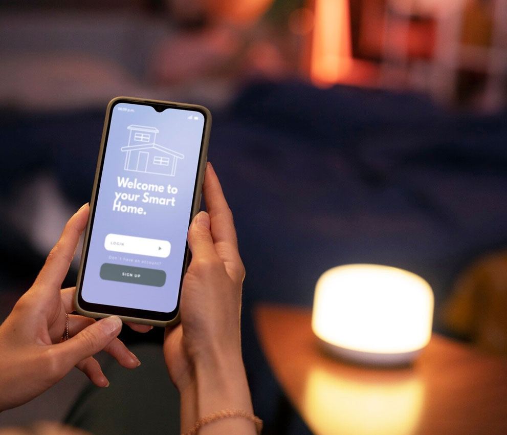 Smart home app login screen on a phone beside a glowing lamp